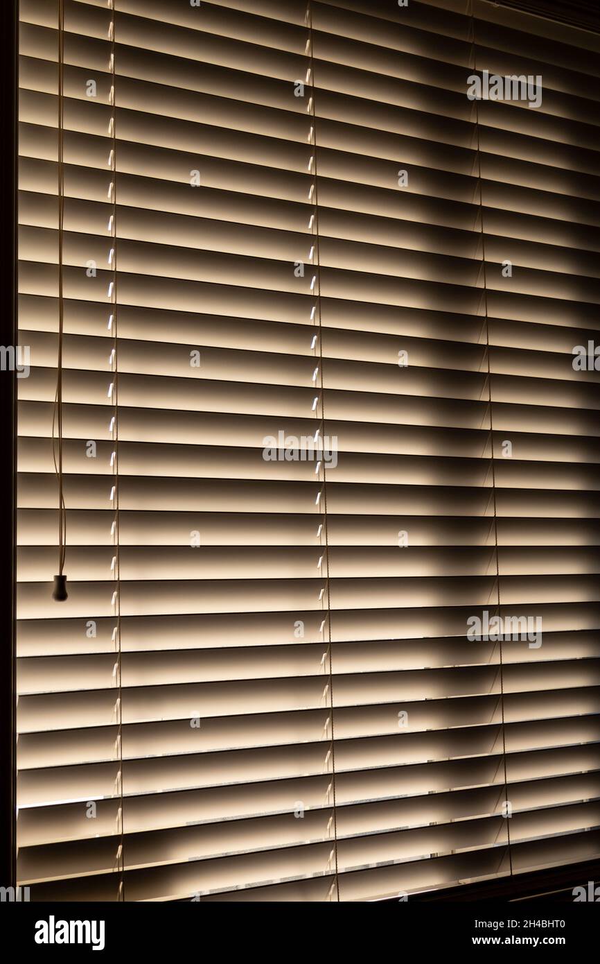 Office blinds, dark inside with sun peaking through from outdoors Stock Photo