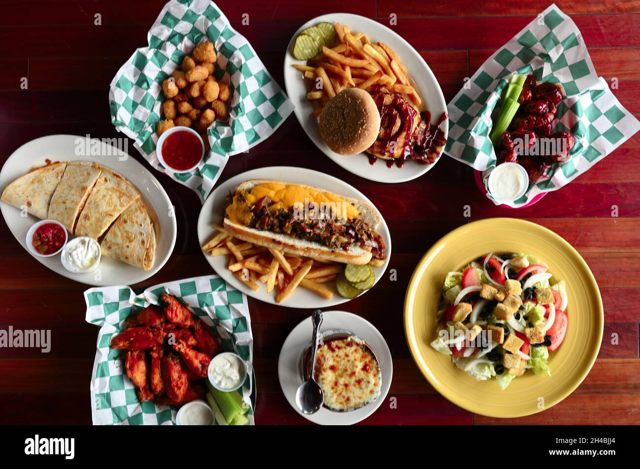 Food Story, American Pub Fare Philly cheesesteak, Buffalo Wings and Cheeseburger plated top view Stock Photo