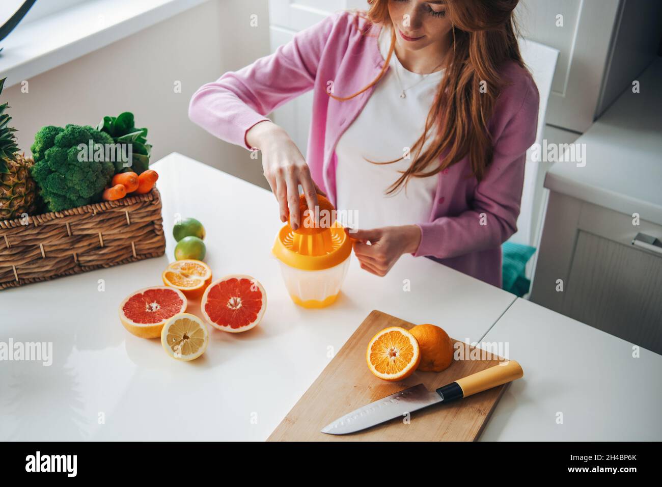 Red hair woman making citrus fruits juice for healthy lifestyle design. Healthy diet. Fruit juice. Stock Photo