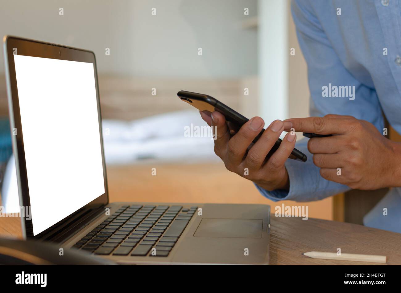 man using mobile smart phone and computer laptop on desk Stock Photo