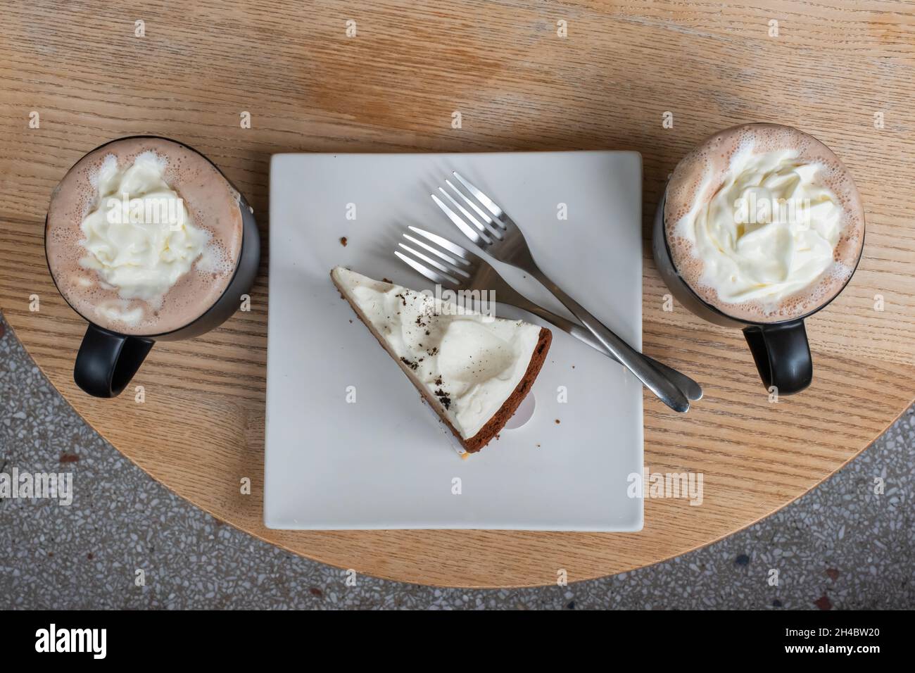 Two cups of mocha and a chocolate cake slice in a plate on a wood table top view Stock Photo