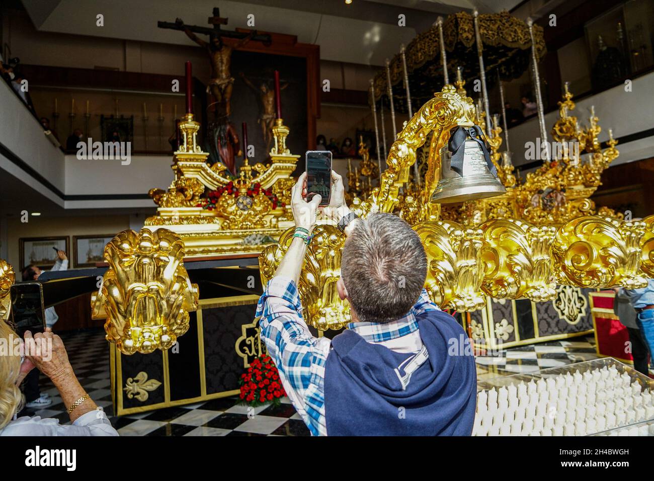 Malaga, Spain. 23rd Oct, 2021. A tourist seen taking photos of the Congregacion de Mena sacred image during the procession.Sixteen brotherhoods participate in an extraordinary procession known as 'La Magna: camino de la gloria' (The great: the way of the glory) along the main streets of the city, as part of activities to commemorate the centenary of brotherhood groups. Credit: SOPA Images Limited/Alamy Live News Stock Photo