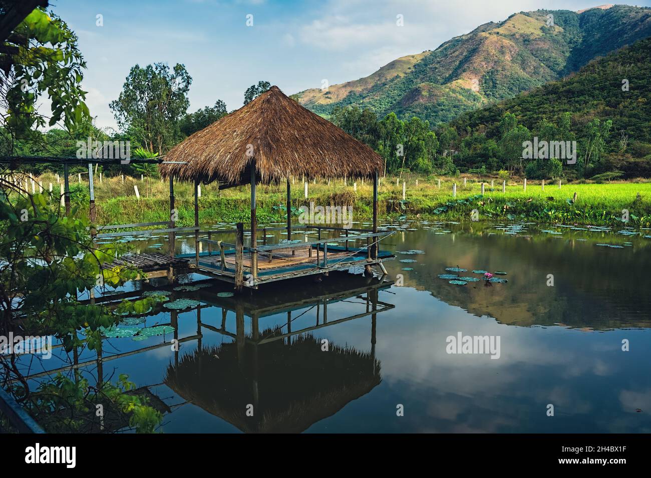 Summer country landscape with gazebo on the small lake among the forest and mountains. Vietnam, Nha Trang Stock Photo