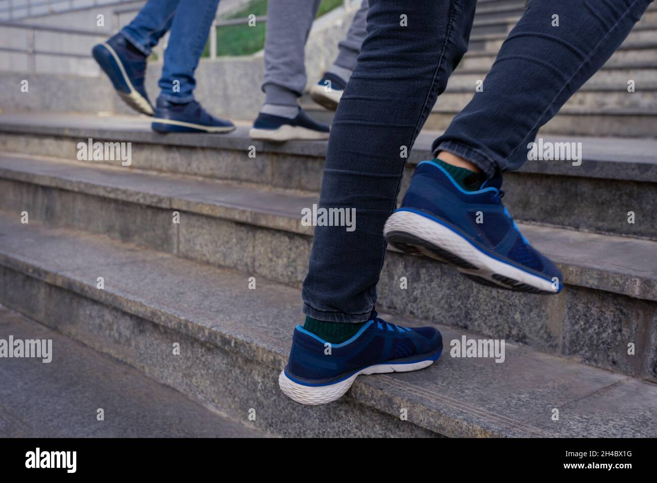 People walking up the stairs. Close up legs in jeans and sport shoes sneakers. Photo with blur in motion. Stock Photo