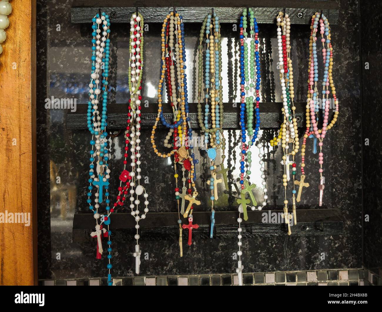 Different colors and varieties of Holy Rosaries hang on a wooden box.The Philippine Government task force against Covid-19 ordered the public and private cemeteries, memorial parks and columbarium throughout the country to be closed from October 29 until November 2 to avoid mass gathering and as prevention for the further spread of the coronavirus infection (Covid-19). Churches in the Philippines will be open to devotees in a limited capacity only to light candles for their dead relatives to ensure all safety protocols and social distancing will be applied. Stock Photo