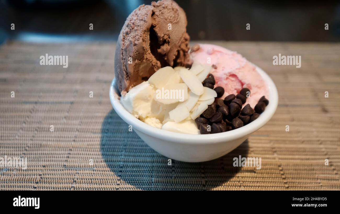 Ice Cream Vanilla Chocolate and Strawberry with Sliced Almonds and Chocolate Chips in a Bowl Stock Photo