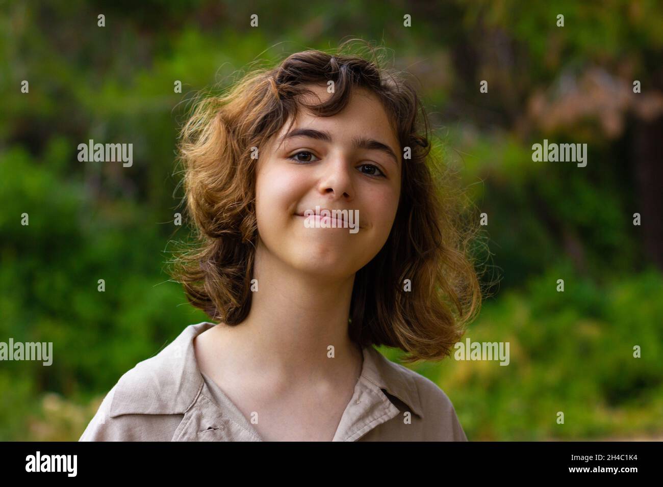 Cute teenager girl smiling to camera. Young girl in the green forest Stock Photo