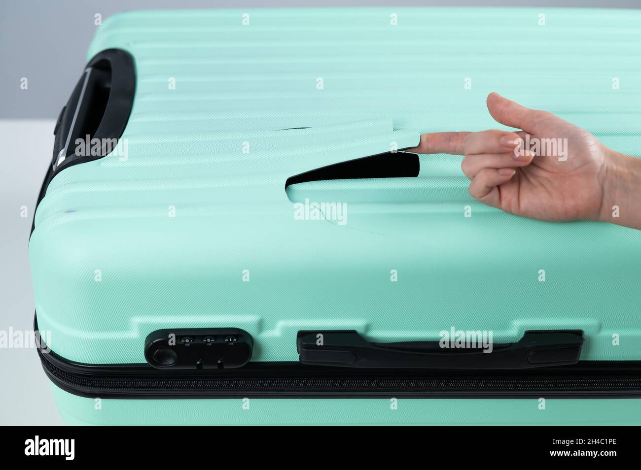 A woman demonstrates a broken suitcase on a white background. Damaged