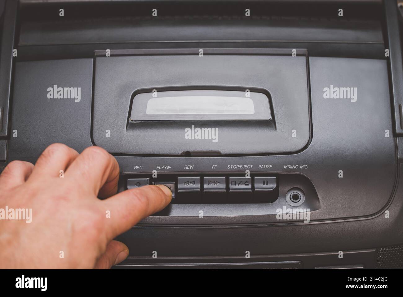 pressing buttons on a tape recorder, hand close-up on a black background Stock Photo