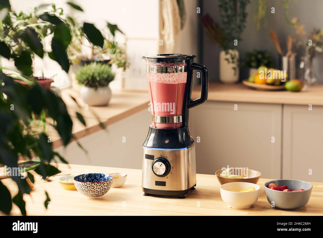 Electric blender with fresh homemade fruit smoothie and group of