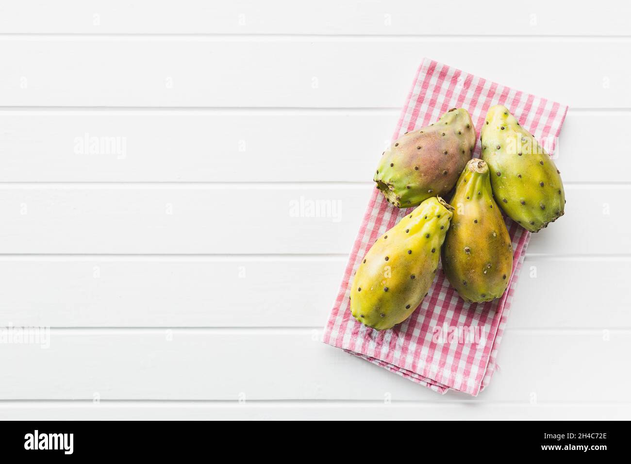 Raw prickly pears. Opuntia or indian fig cactus on white table. Top view. Stock Photo
