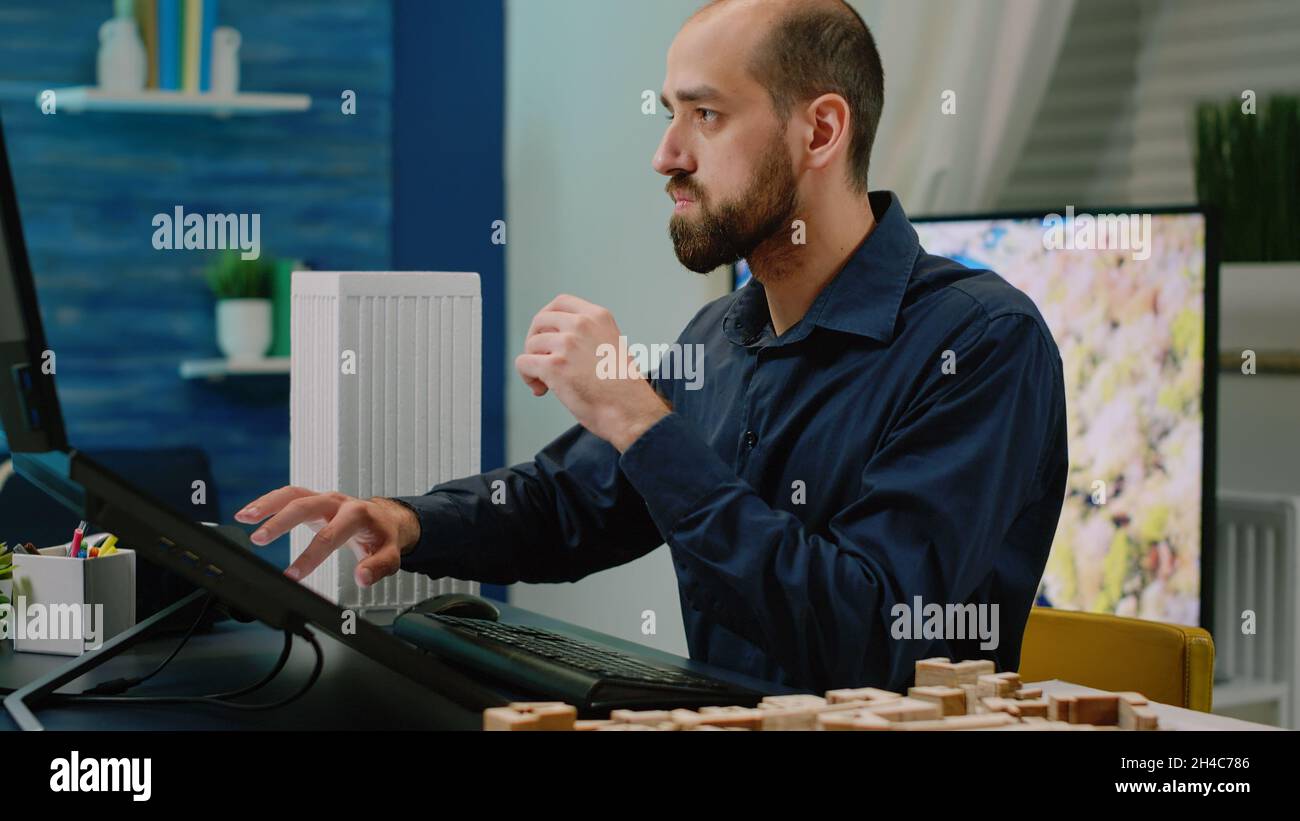 Close up of man working on computer with building model and maquette ...
