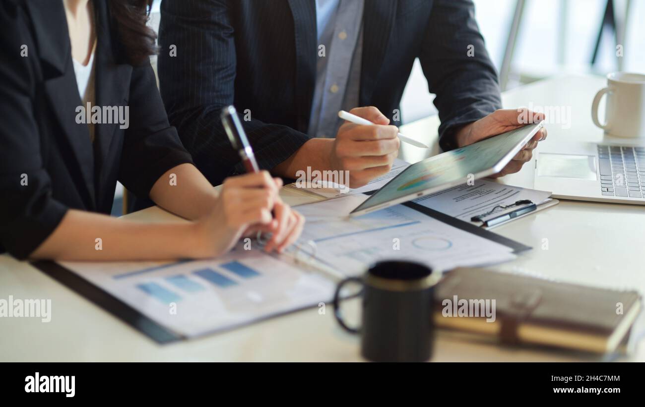 Business financial team cooperating on their working process, using digital tablet to analyse data at their workplace. Stock Photo