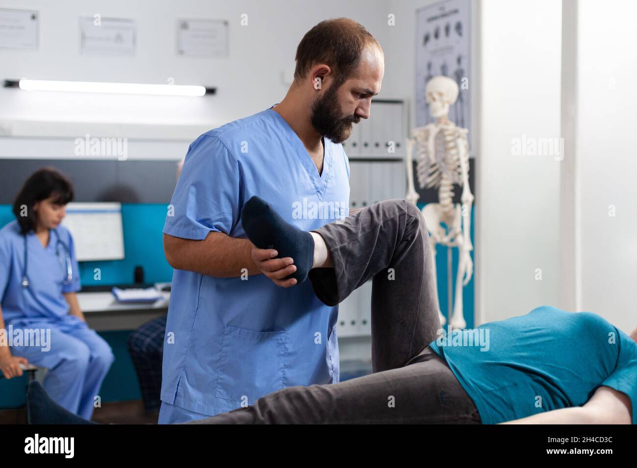 Chiropractic physician helping aged woman with leg muscle pain in