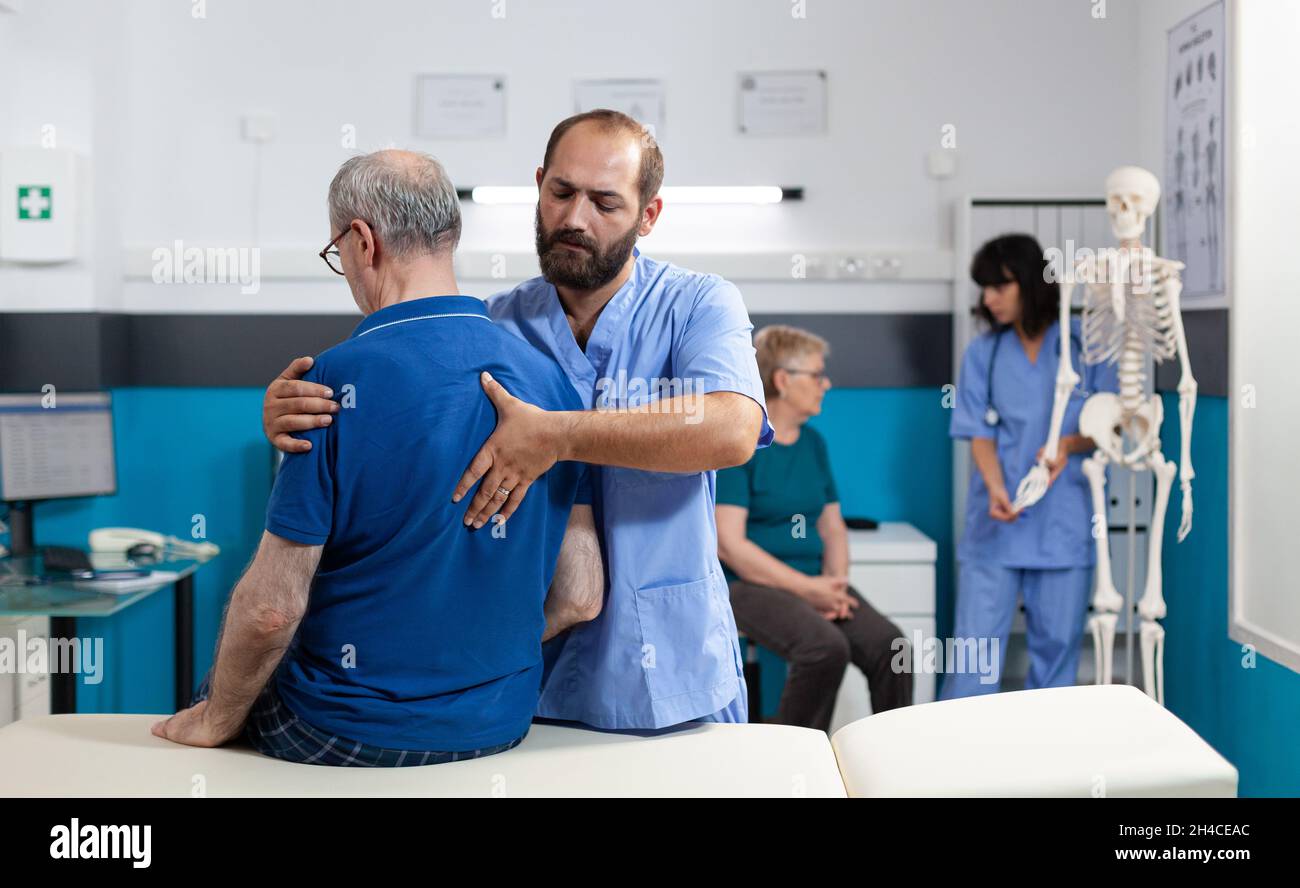 Chiropractor treating retired patient with back pain for physical