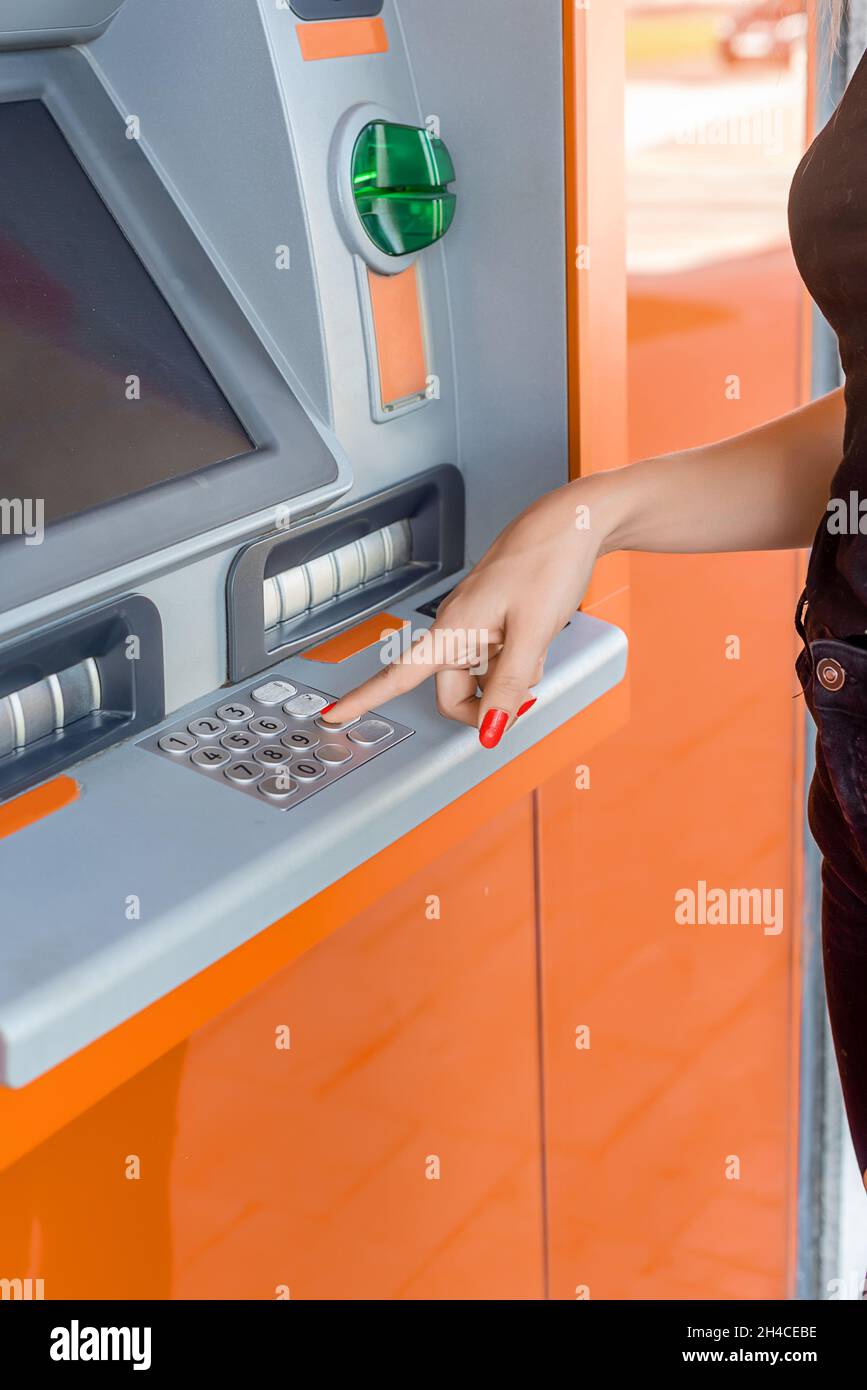 Woman's hands entering the secret code at a bank ATM machine Stock Photo