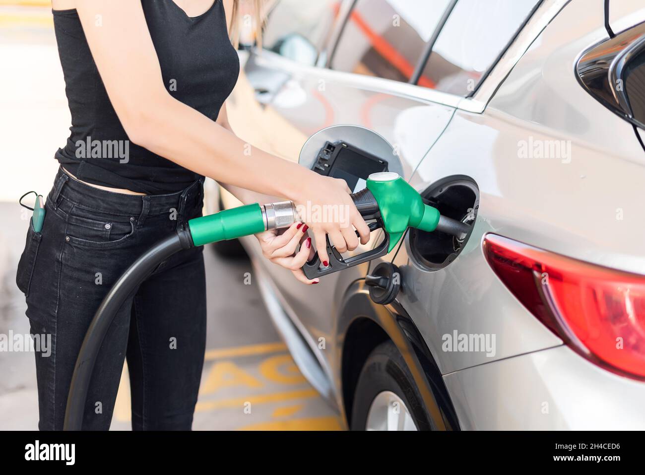 Close up of a young woman getting gas in her car at a gas station Stock Photo