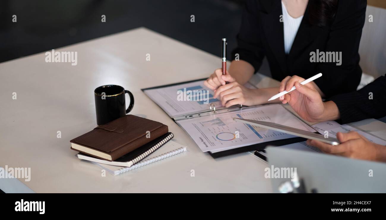 Close up of business people discussing a financial plan with paperwork and digital tablet Stock Photo