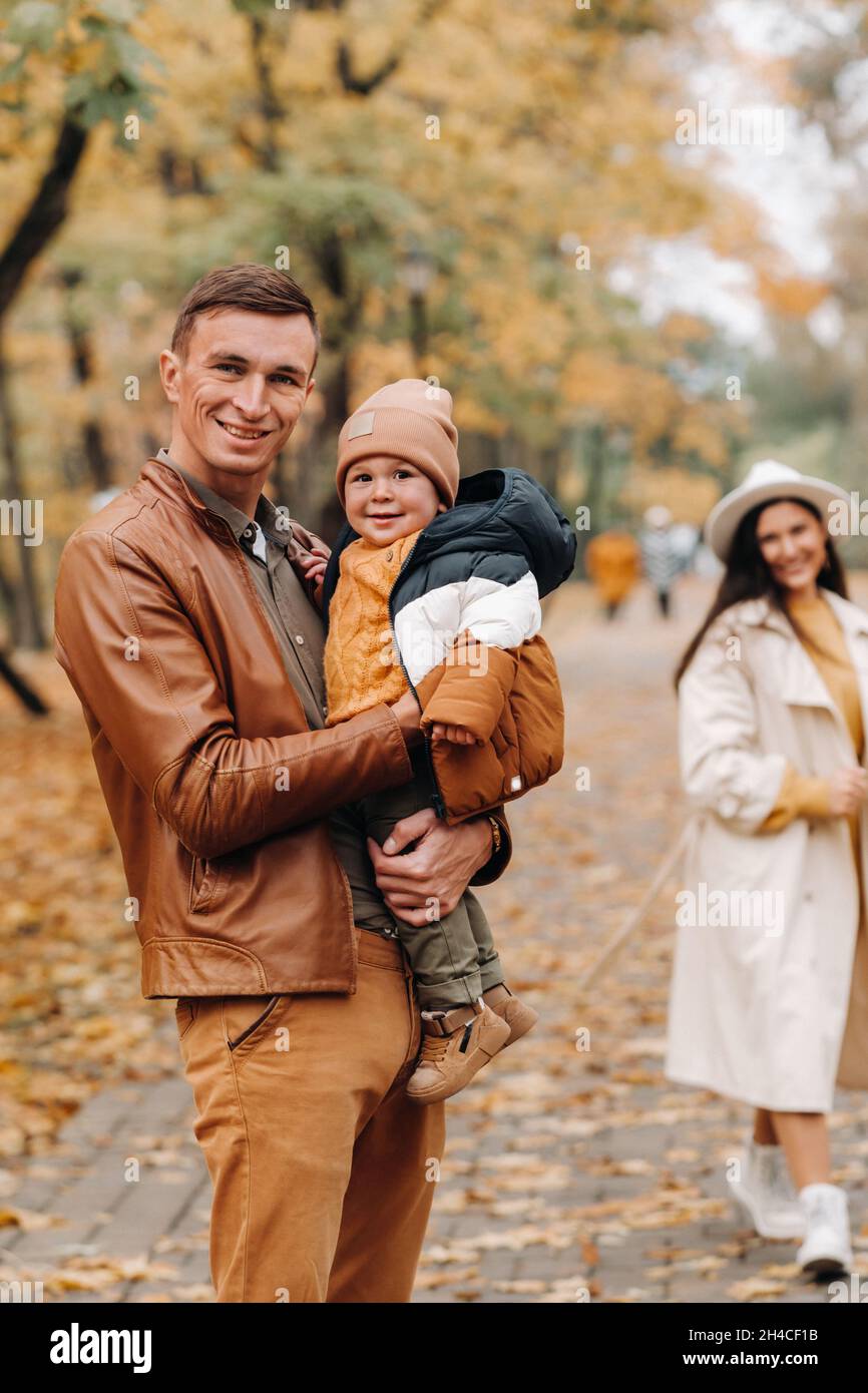 Father and mother with son walking in the autumn Park. A family walks ...