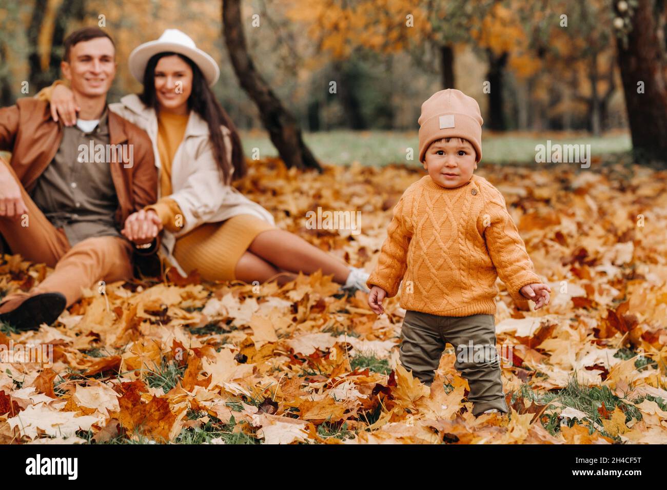 Father and mother with son walking in the autumn Park. A family walks ...