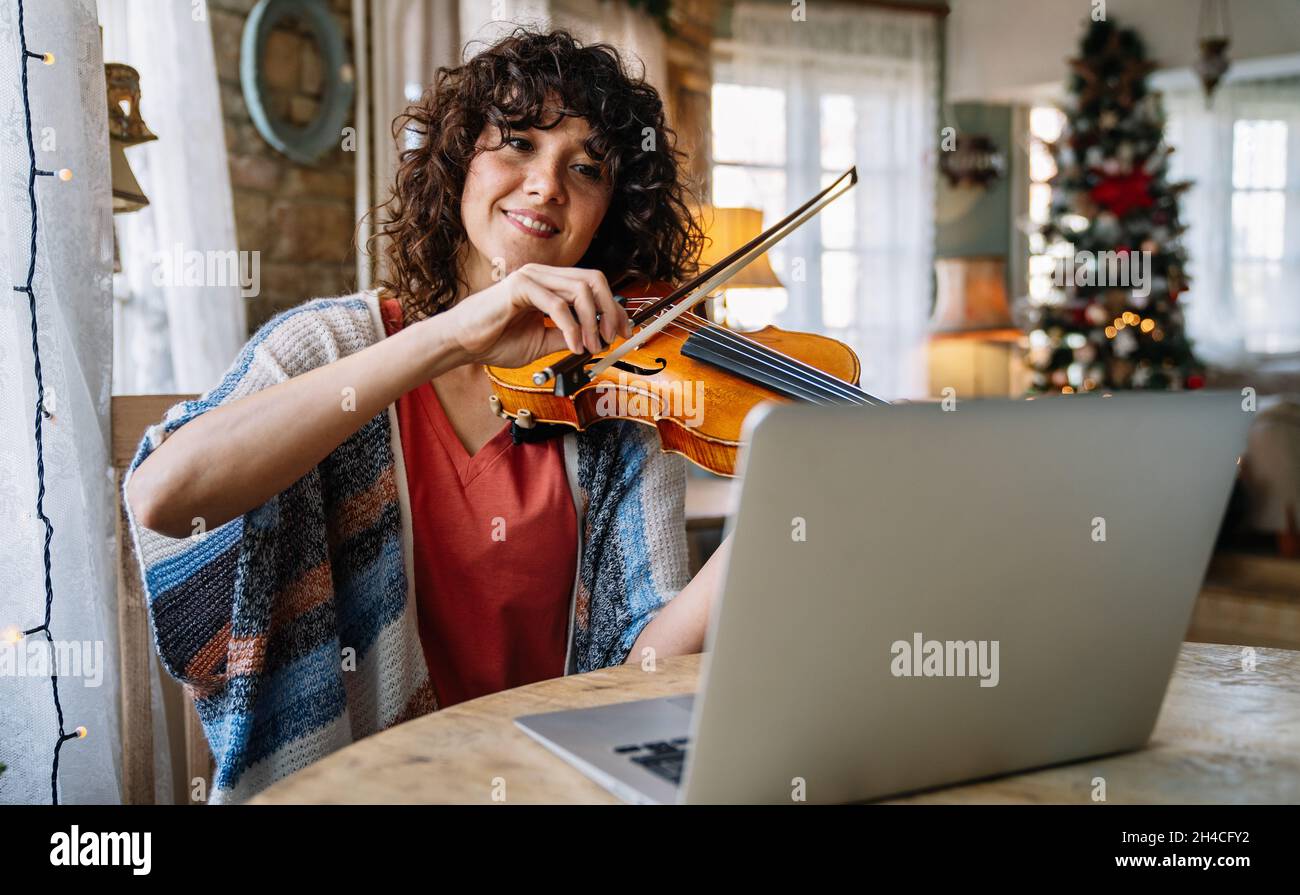 Woman music teacher teaching how to play a song the violin online during a video call Stock Photo