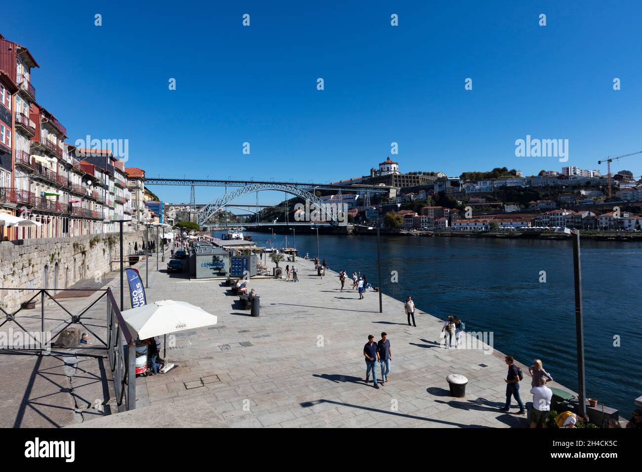 Fußgängerpromenade entlang des Douro in der Altstadt von Porto. Im Hintergrund ist die Brücke Pond Luis I zu sehen. Menschen flanieren, sind nicht zu . Stock Photo