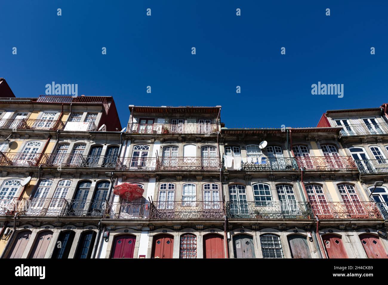 Häuserfronten entlang der Cais da Ribeira in Portugal. Altbaufront mit schönen Balkonen und bunten Sonnenschirmen. Stock Photo