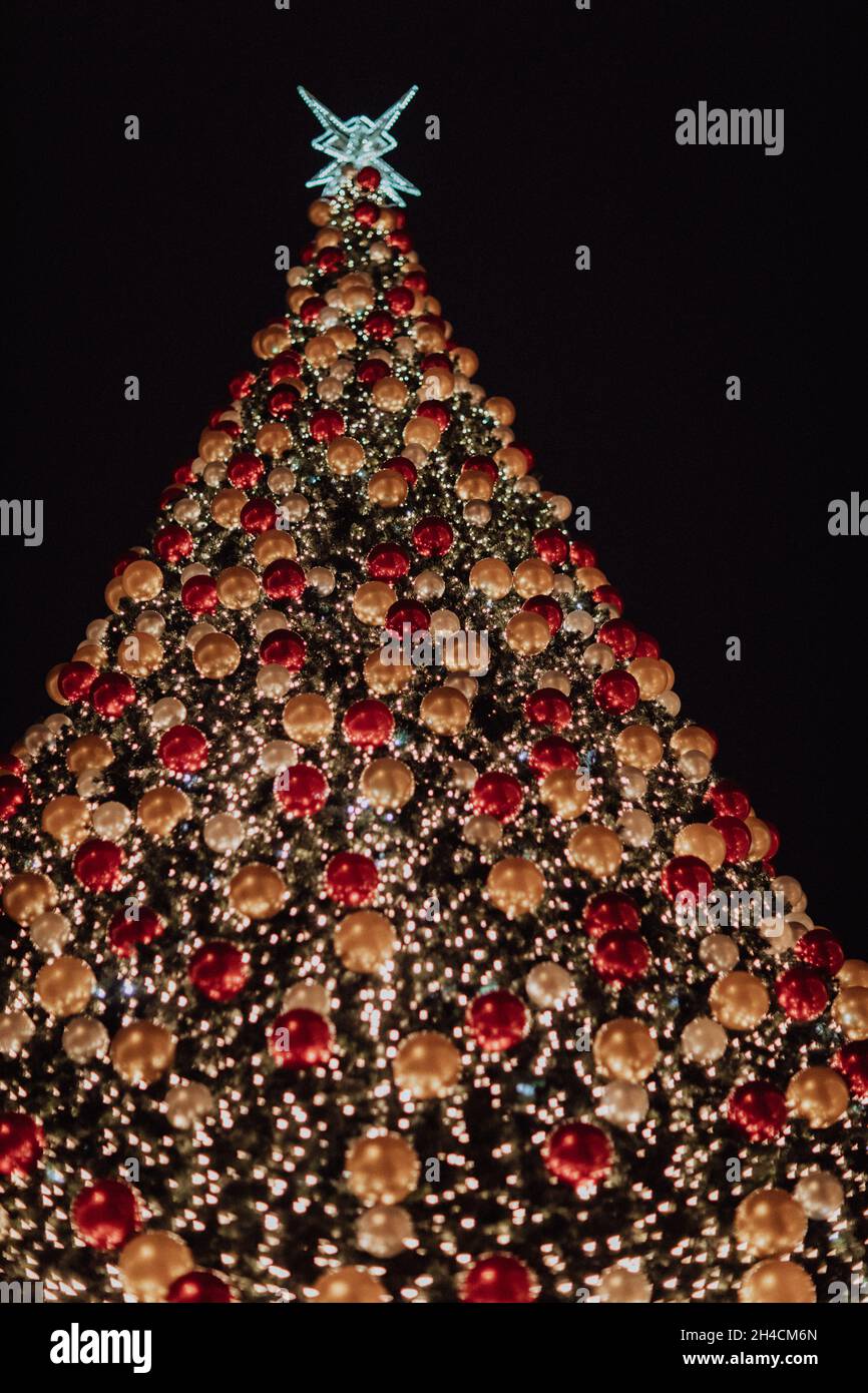 Very tall outdoor Christmas tree with lots of lights and globes Stock