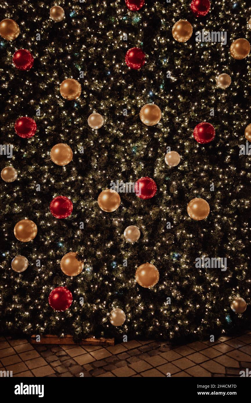 Very tall outdoor Christmas tree with lots of lights and globes Stock