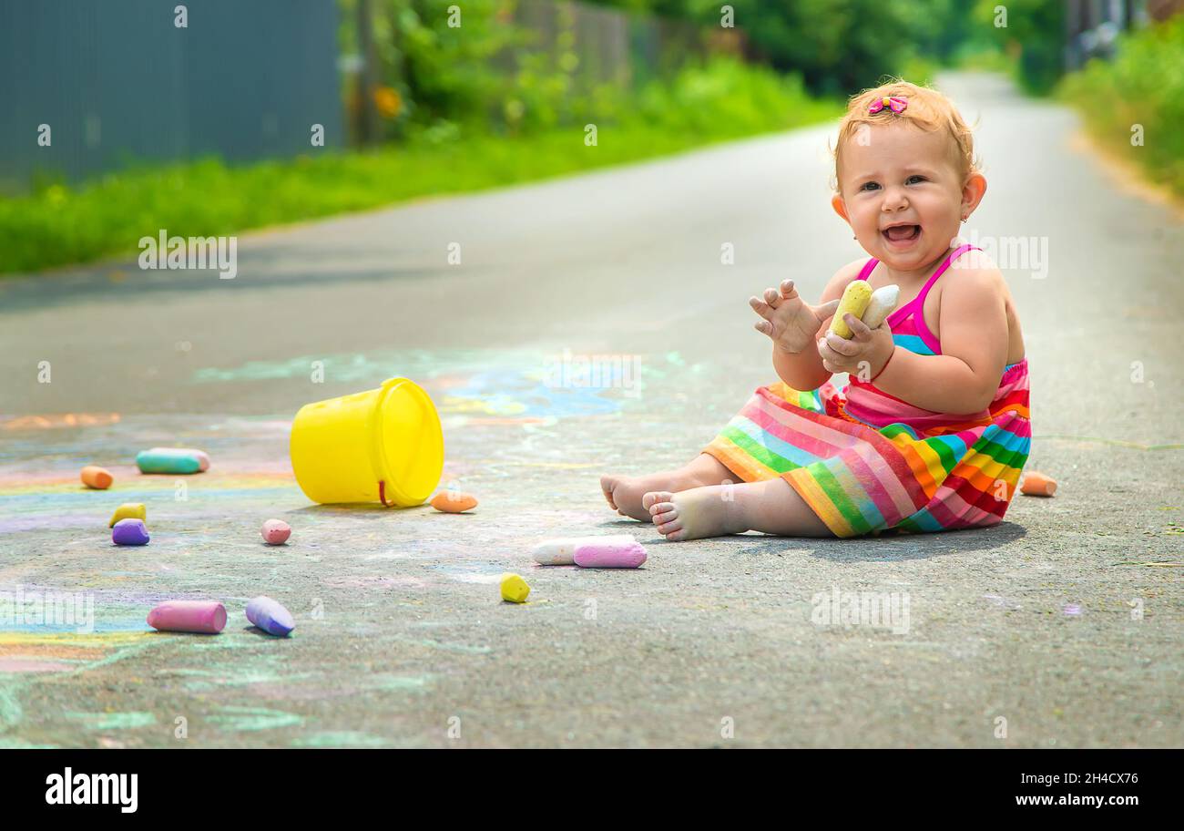 The child draws with chalk on the asphalt. Selective focus. Kid Stock ...