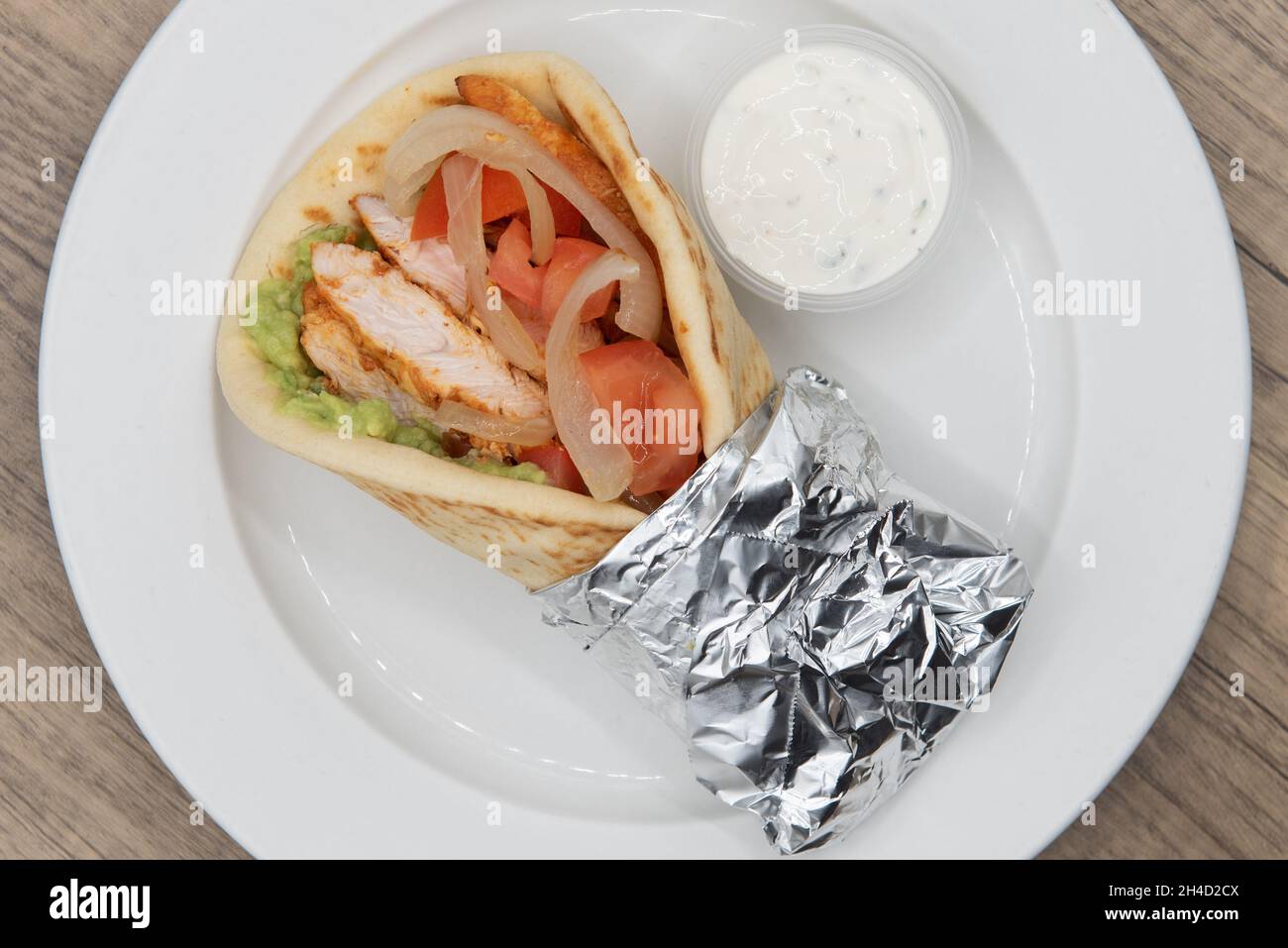 Overhead view of loaded Tikka chicken fajita wrap bursting with fillings in a freshly baked pita