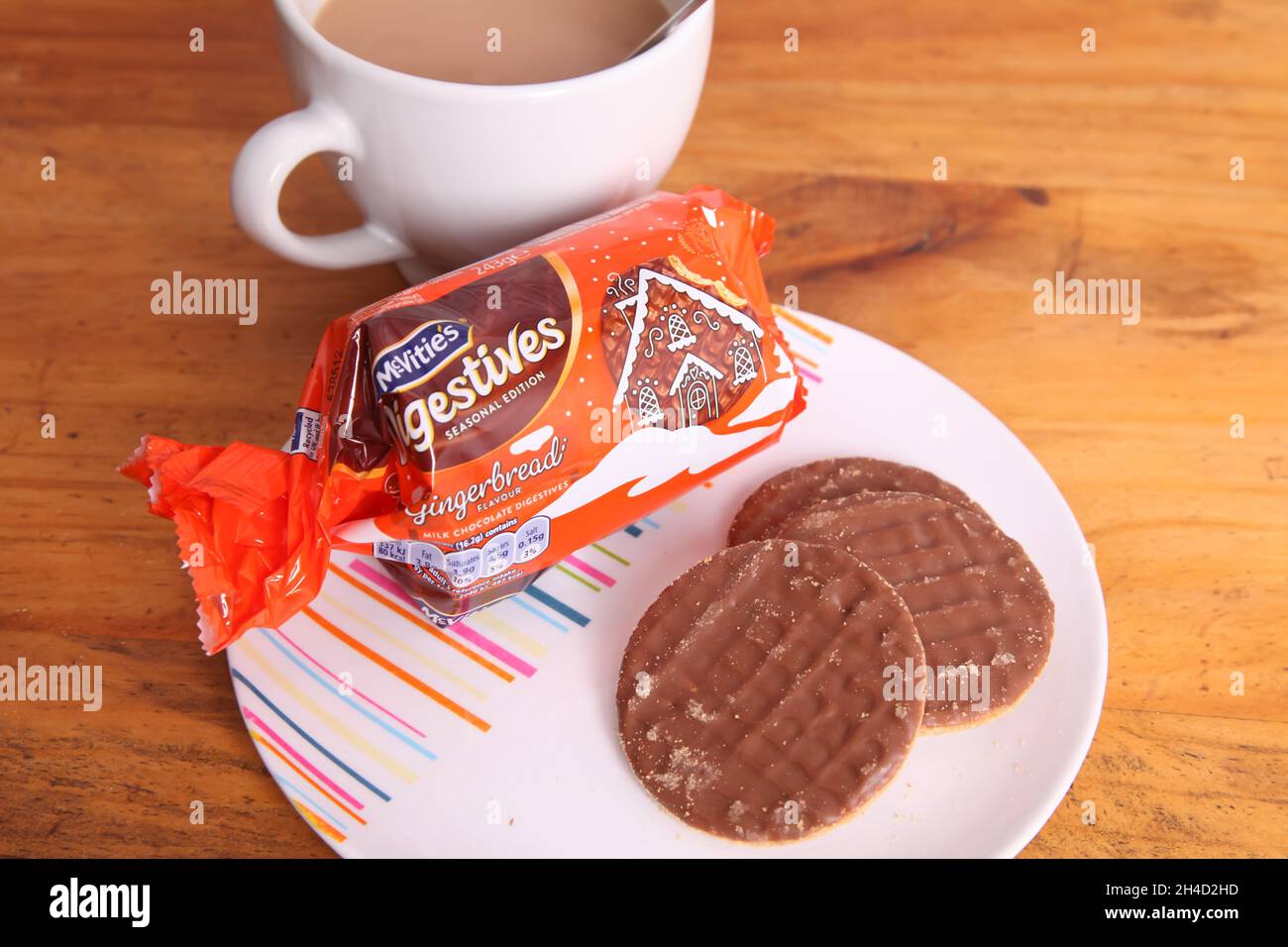 Plate of McVities gingerbread chocolate digestive biscuits with open packet and cup of tea Stock