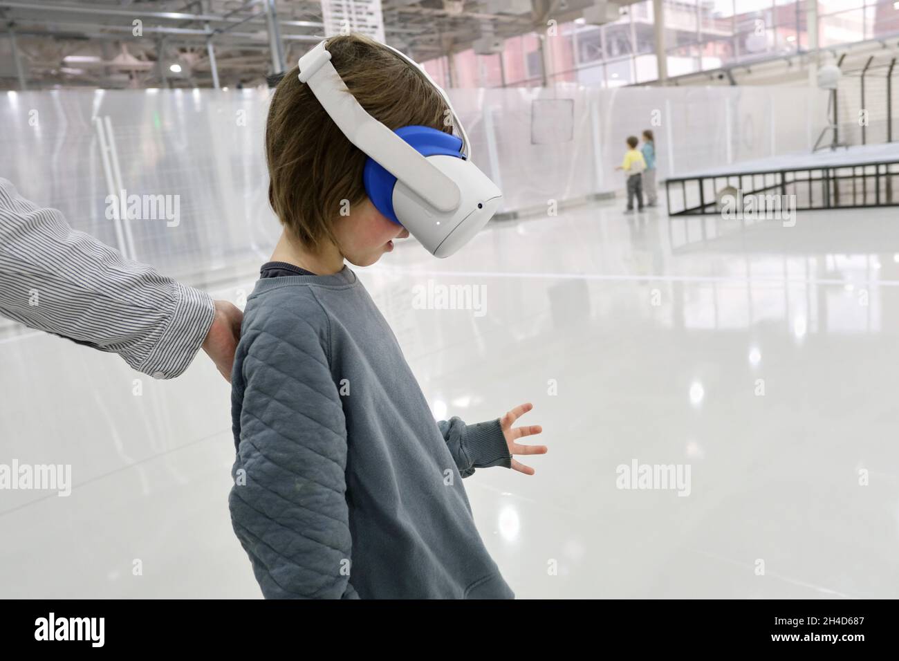 Side view of boy wearing modern VR goggles immersing in cyberspace in spacious showroom Stock Photo