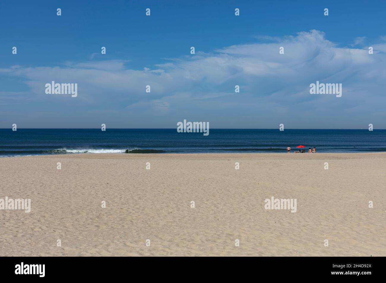 Leerer Strand mit rotem Sonnenschirm und zwei Strandbesuchern, nicht erkennbar) in Espinho Stock Photo