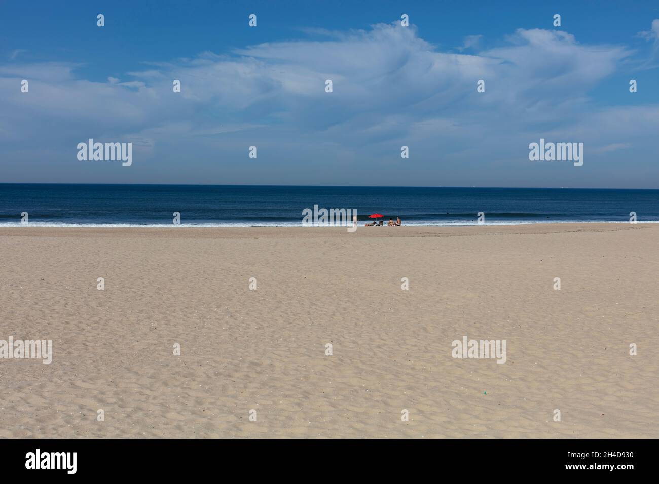 Leerer Strand mit rotem Sonnenschirm und zwei Strandbesuchern, nicht erkennbar) in Espinho Stock Photo
