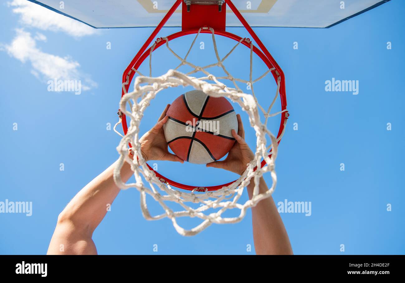 Basketball Player Throws The Ball Into The Hoop On Sky Background basketball-player-throws-the-ball-into-the-hoop-on-sky-background