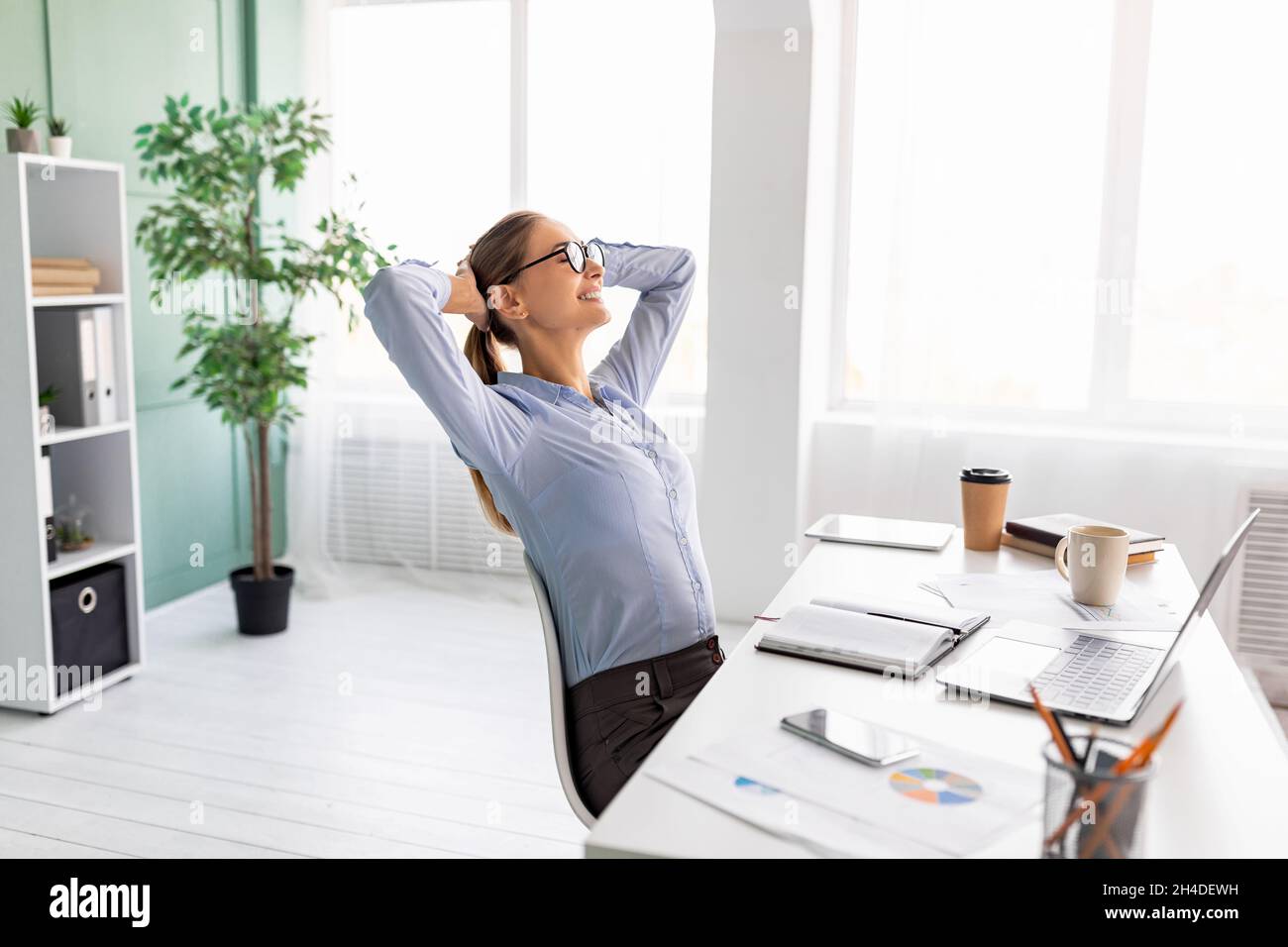 Time for break. Successful lady leaning back in her chair and putting