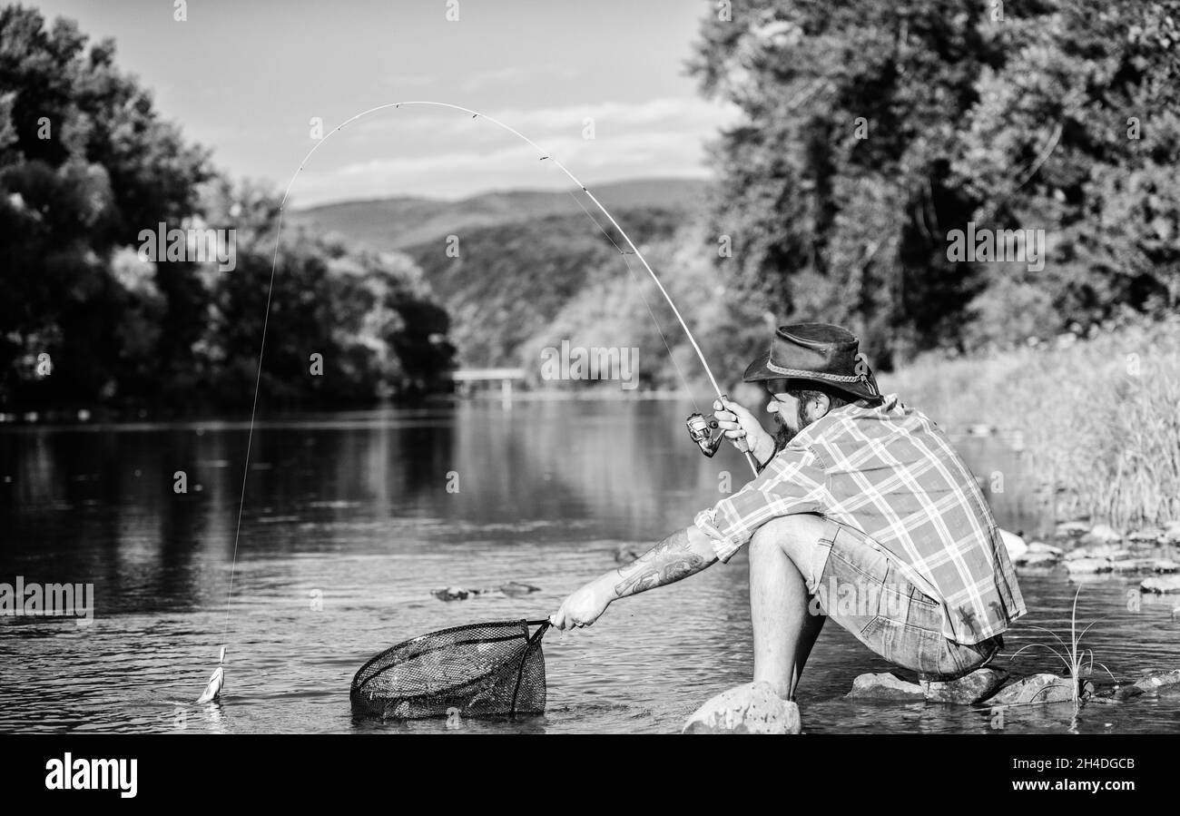 Casting off. mature bearded man with fish on rod. successful fisherman in lake. hipster fishing with spoon-bait. fly fish hobby of man. Hipster in Stock Photo