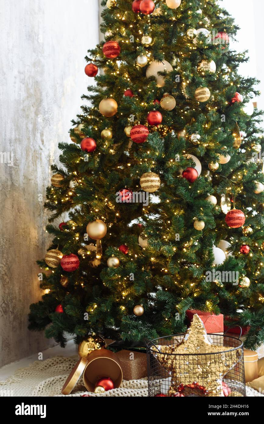 Christmas tree with red and gold balls and gold garland lights in a ...