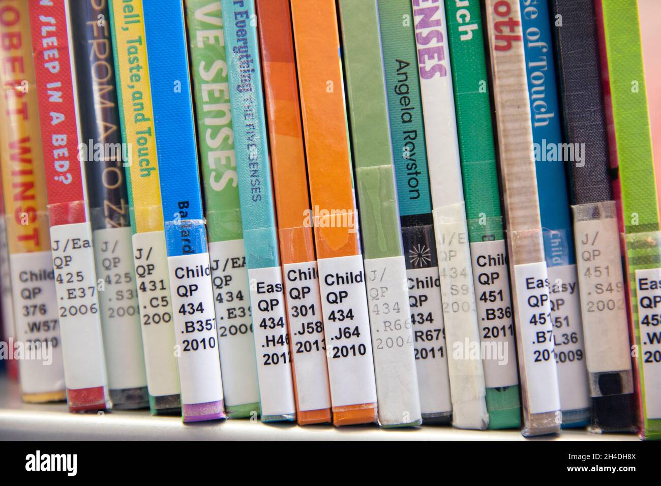 Close-up of books with Library of Congress Classification call numbers on book spines on the shelf in a children’s science section of a public library Stock Photo