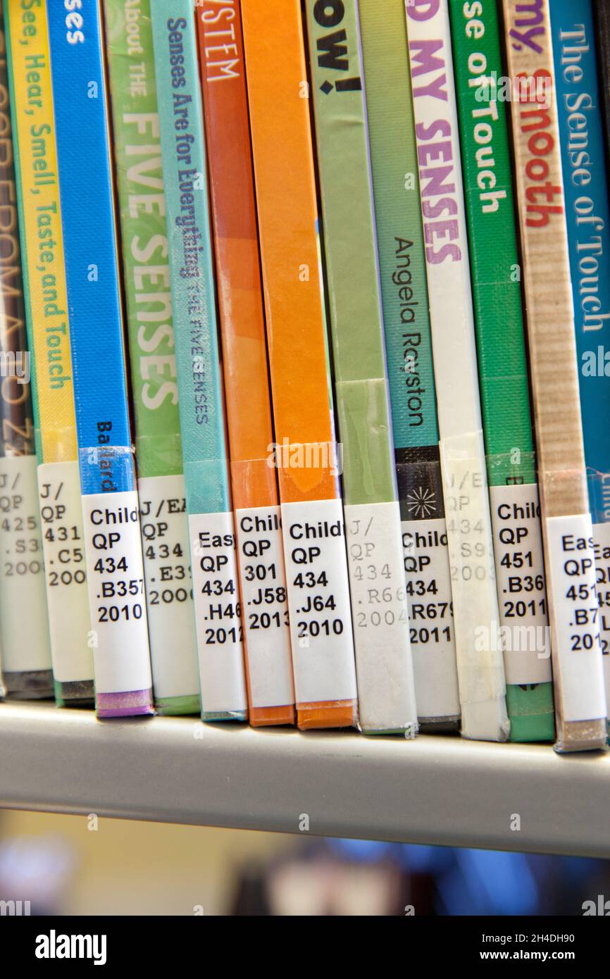 Close-up of books with Library of Congress Classification call numbers on book spines on the shelf in a children’s science section of a public library Stock Photo