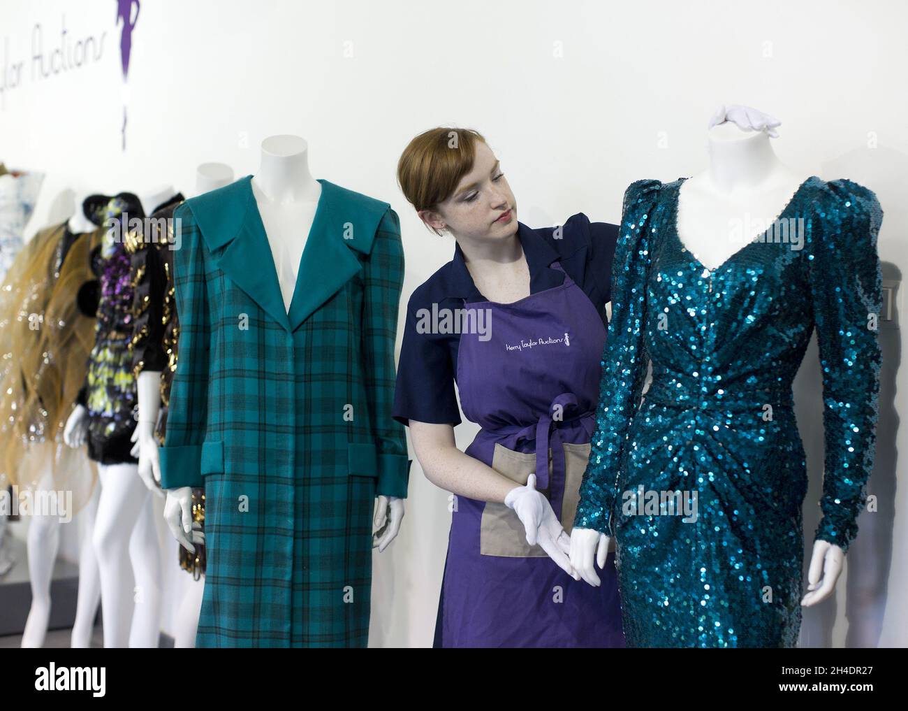 Auction assistant Lucy Bishop puts the finishing touches to two dresses worn by Princess Diana, both in shades of teal-blue/green, part of the June 14th  Passion for fashion auction at Kerry Taylor Auctions in south London.  (Left) Lot 208, a practical large tartan check with wide padded shoulders with Diana's trademark sailor-collar, designed by Elizabeth and David Emanuel, estimate £10,000-15,000.  (Right) Lot 210, a glamorous gown split to the knee by designer Catherine Walker, estimate £80,000-100,000. Stock Photo