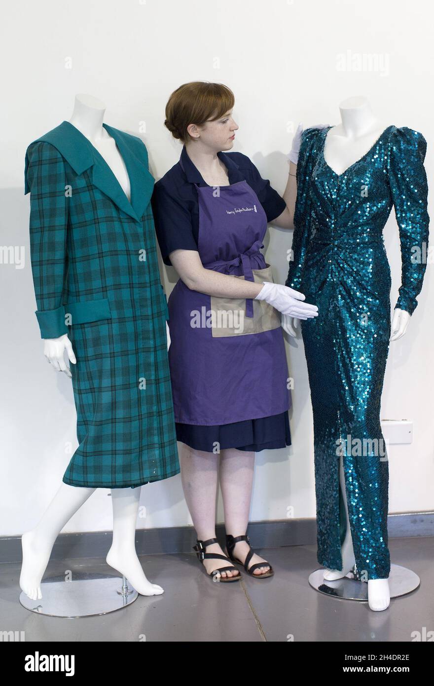 Auction assistant Lucy Bishop puts the finishing touches to two dresses worn by Princess Diana, both in shades of teal-blue/green, part of the June 14th  Passion for fashion auction at Kerry Taylor Auctions in south London.  (Left) Lot 208, a practical large tartan check with wide padded shoulders with Diana's trademark sailor-collar, designed by Elizabeth and David Emanuel, estimate £10,000-15,000.  (Right) Lot 210, a glamorous gown split to the knee by designer Catherine Walker, estimate £80,000-100,000. Stock Photo
