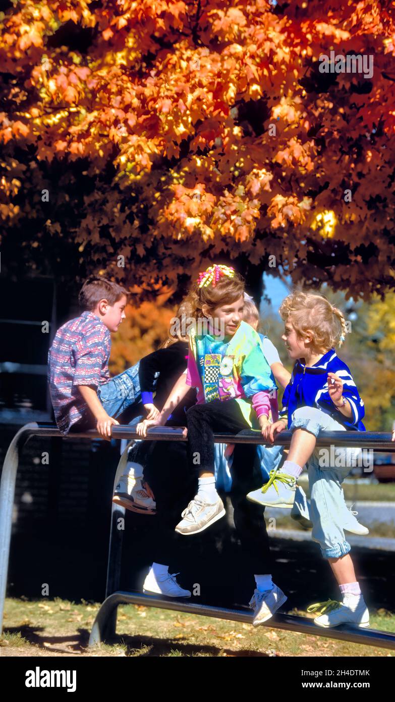 School children play on school playground equipment in the 1980s. Most playground equipment of that era and before has been removed for safety. Stock Photo
