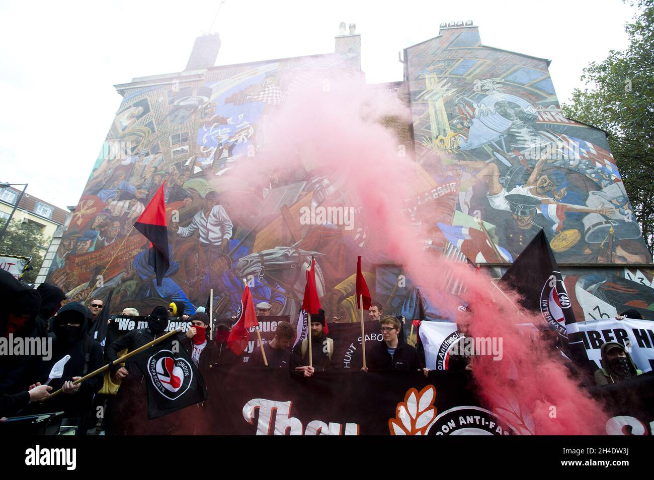Class War activists throw gas canisters as they gather by the Battle of Cable Street mural to commemorate its 80th anniversary, which took place on Sunday 4 October 1936 in east London, when anti-fascists clashed with Oswald Mosley's British Union of Fascists in a march through Whitechapel. Picture date: Saturday October 9, 2016. Photo credit should read: Isabel Infantes / EMPICS Entertainment. Stock Photo
