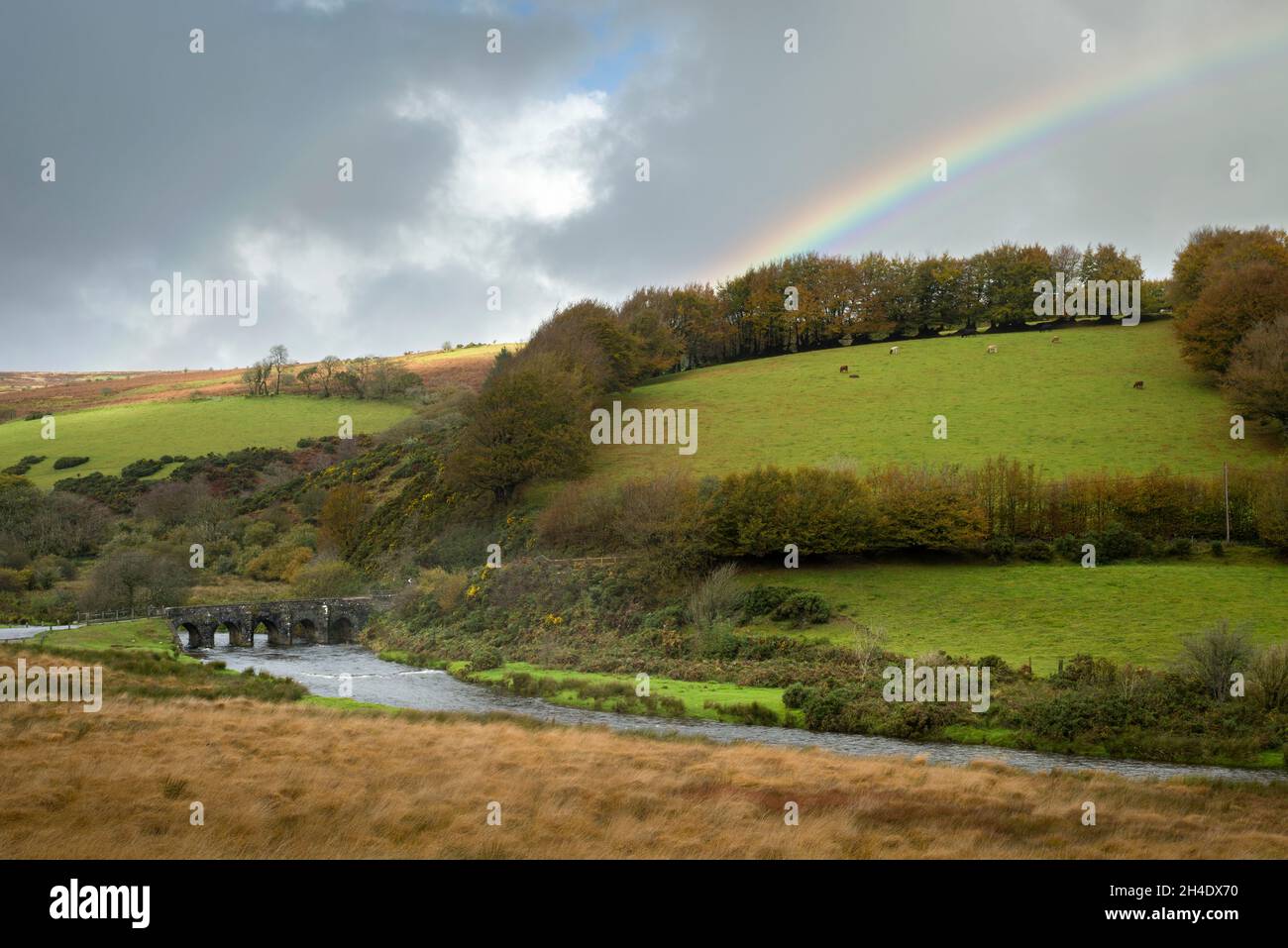 A rainbow over the medieval Landacre Bridge spanning the River Barle in autumn near Withypool in Exmoor National Park, Somerset, England. Stock Photo