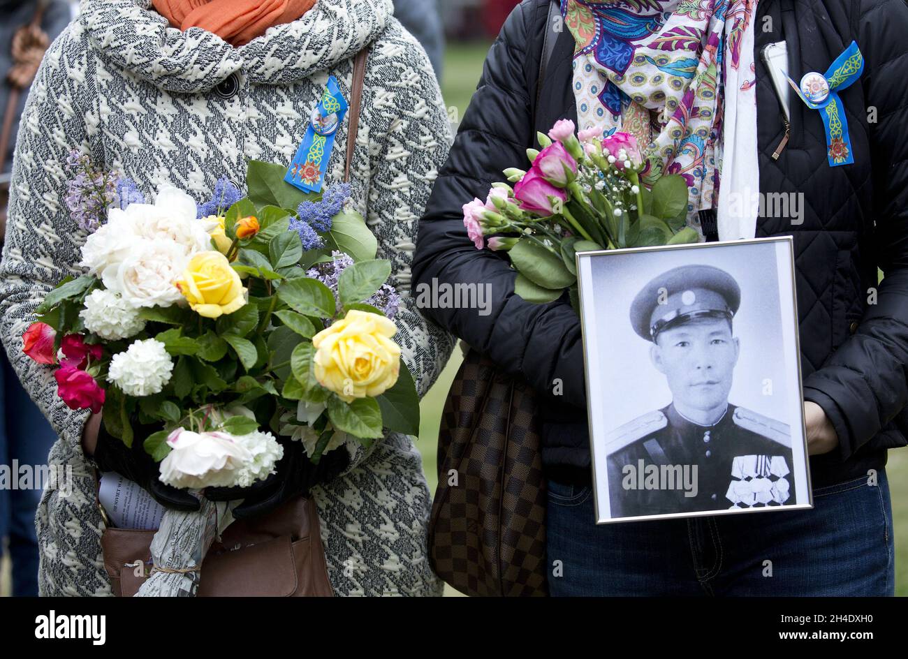 Women hold flowers and a picture of a Soviet War veteran during Victory ...