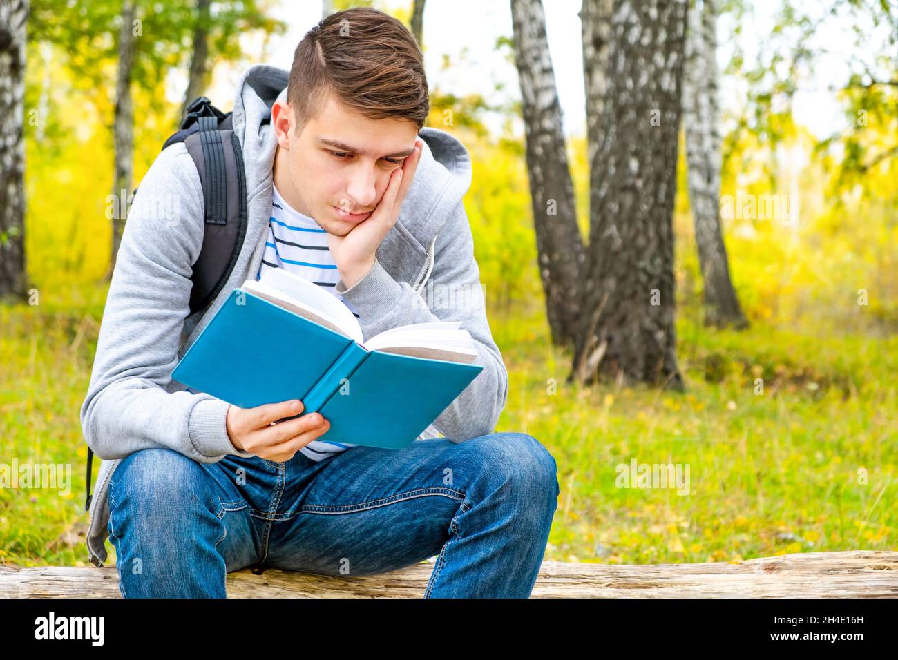 Sad Young Man read a Book in the Forest Alone Stock Photo - Alamy
