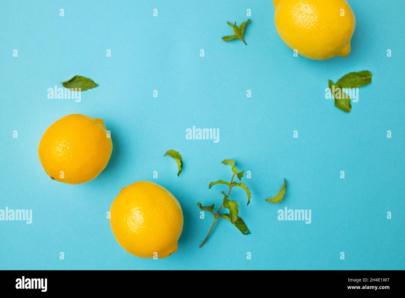 Ripe lemons with mint leaves isolated on bright blue background with copy space for your text. Top view. Flat lay pattern, banner. Frame made of fresh Stock Photo