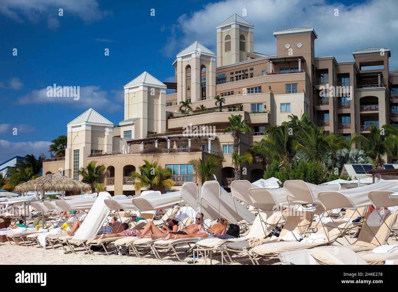 Grand Cayman, Cayman Islands - March 8, 2013:  Guests of luxury hotel relax on lounge chairs on the beach in Grand Cayman, Cayman Islands. Stock Photo